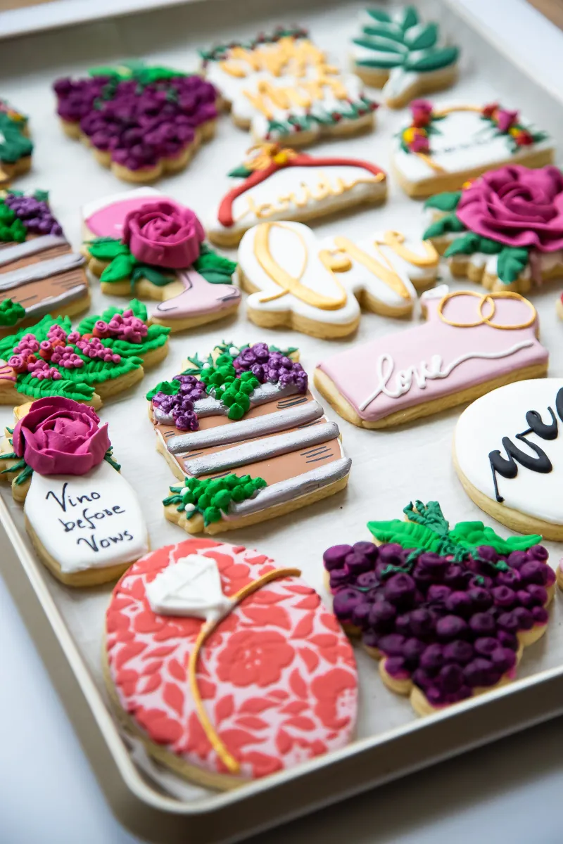 Wine and grape themed bridal shower cookies with buttercream roses, wedding dress and gold lettering
