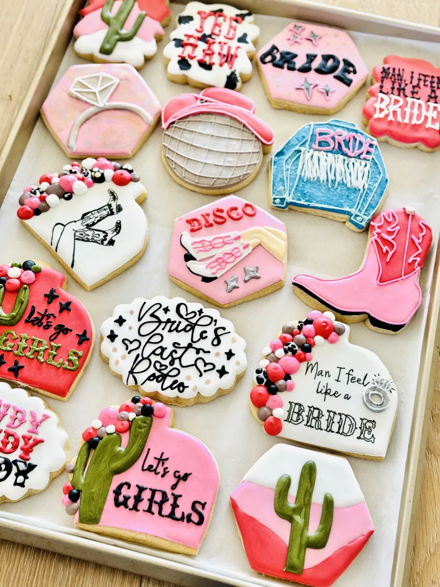 Pink cowgirl bachelorette party cookies with cowboy boots, disco ball, cactus and Bride's Last Rodeo lettering