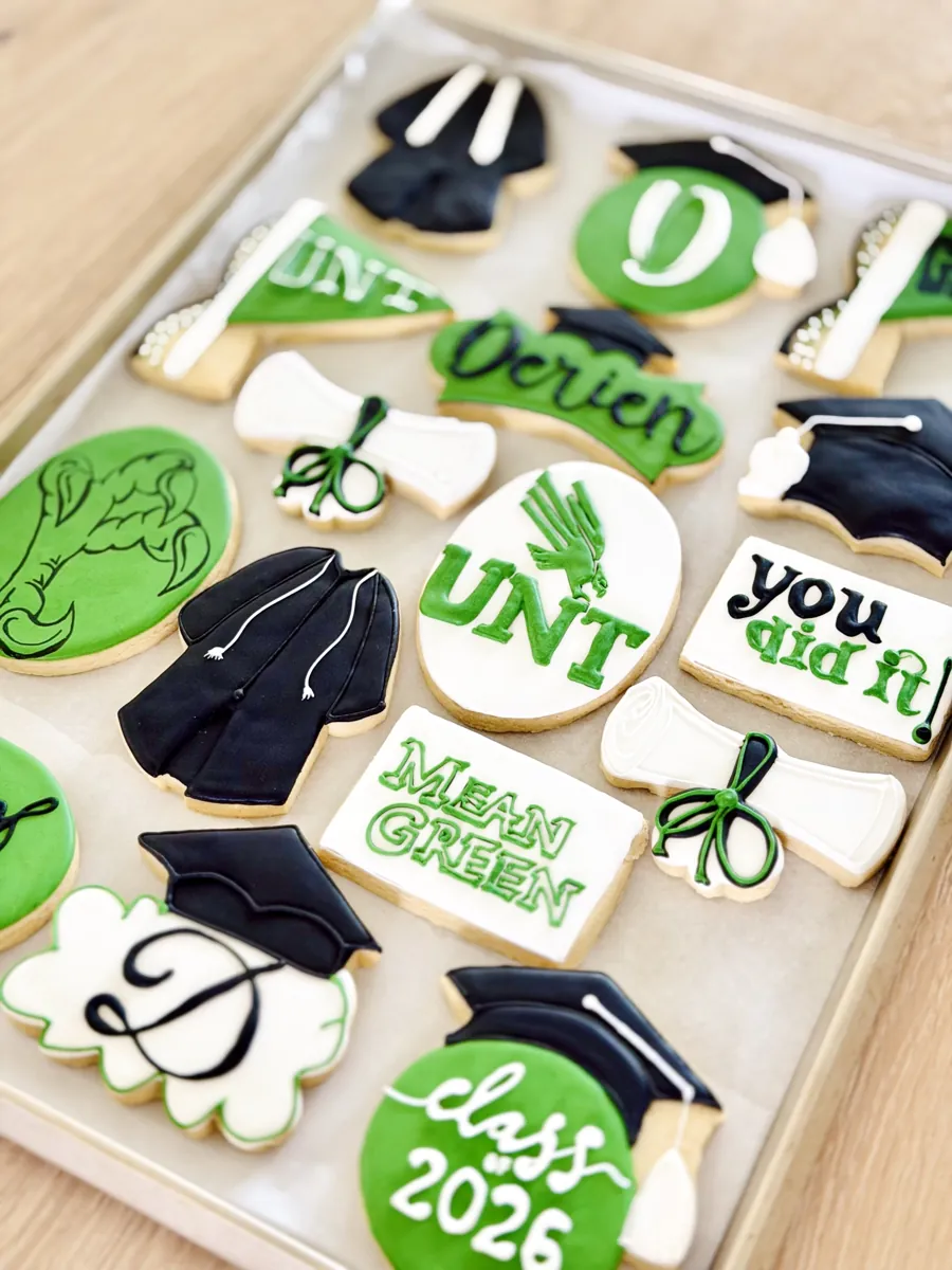 Green and black graduation cookies with caps, gown, diploma scrolls, pennant and Class of 2026 lettering