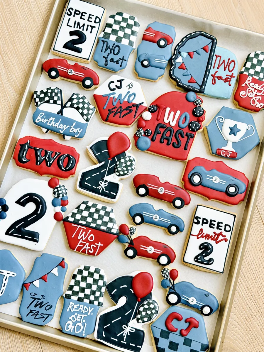 Two Fast race car second birthday cookies with checkered flags, red and blue race cars, speed limit sign and number two
